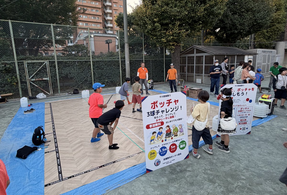 校庭の仮設コートと「ボッチャ3球チャレンジ!」の看板、集まった子どもたちと大人