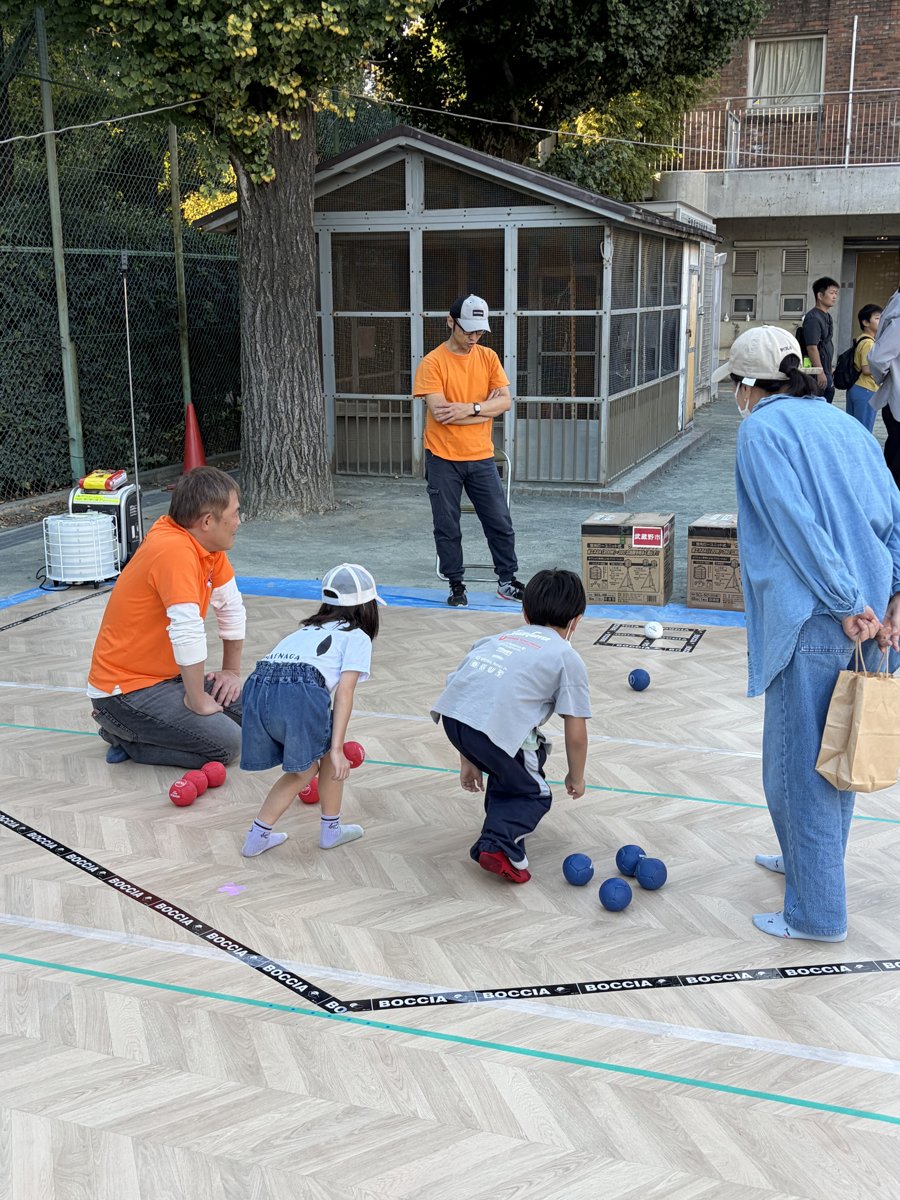 ターゲットに向かってボールを投げる子どもと、見守る大人