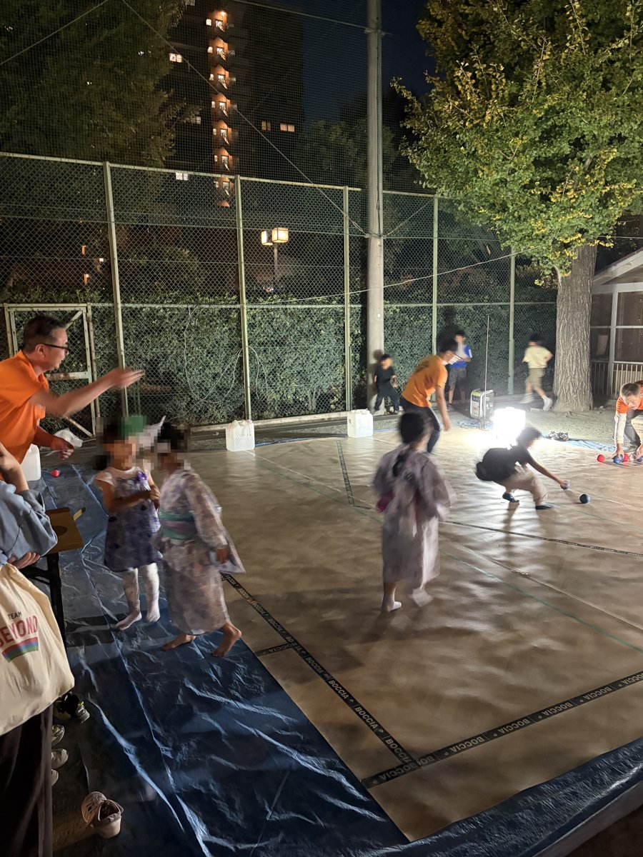 夜、投光器の明かりの下でボールを投げる子どもたち