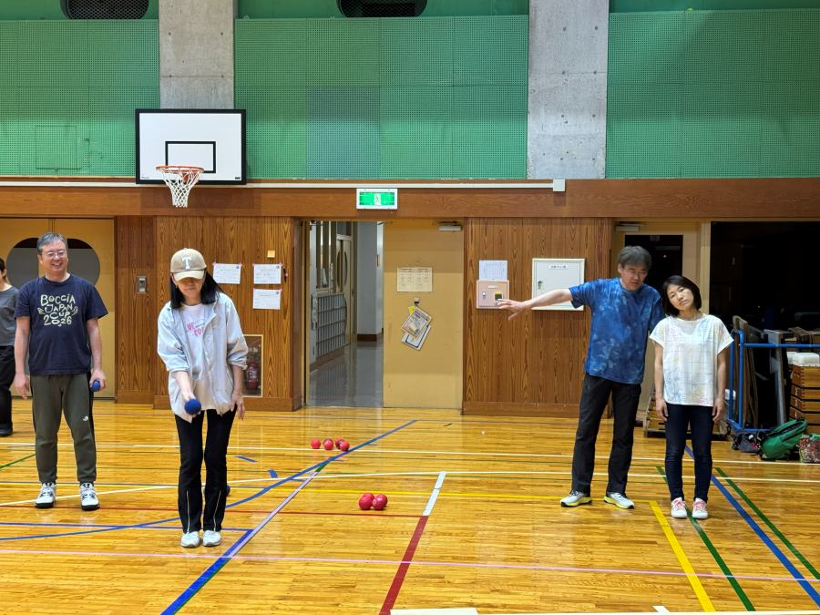 千川小学校の体育館で、参加者がボールを構えて投球の順番を待っている様子