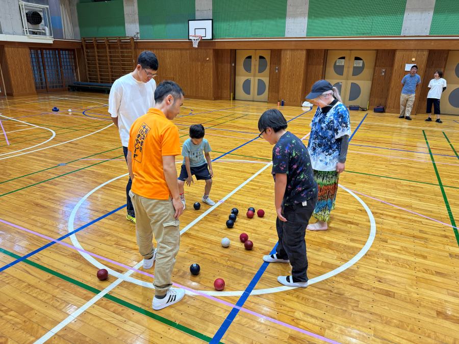 体育館のセンターサークルに集まったボールを、参加者が囲んで見ている様子