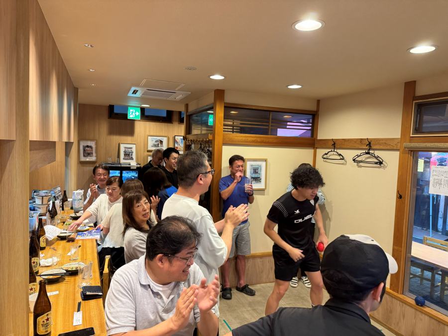 店内で参加者が手を叩いて投球を応援している様子